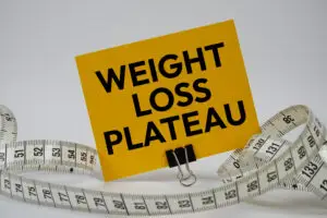 Weight Loss Plateau text with measure tape on white background